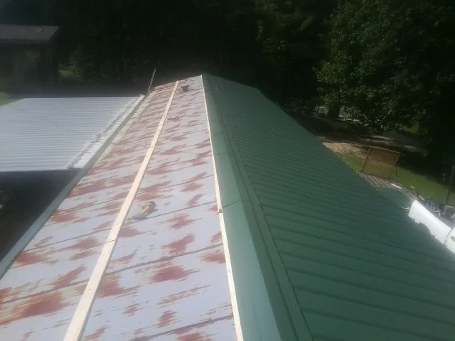 Old rusted panels beside newly installed green metal roofing — Wind Damage Roof Repair by Roofing Brothers in West Orange