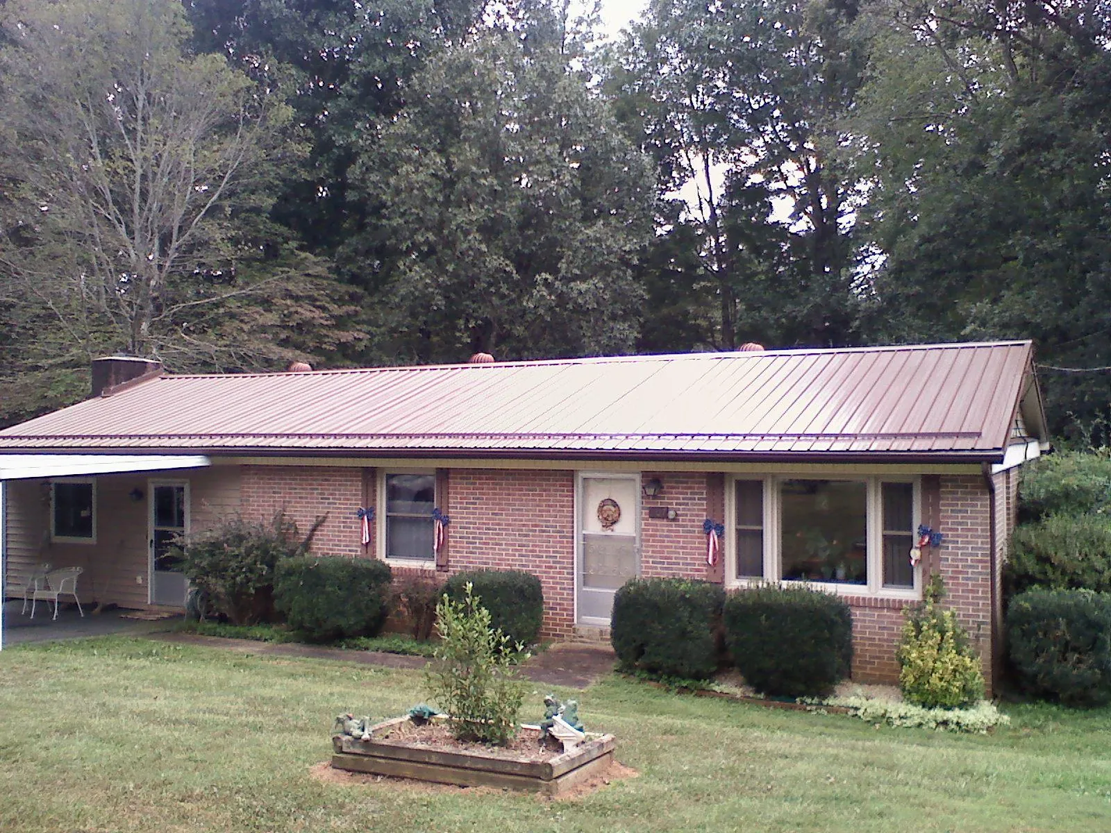 Bronze metal roof on a brick ranch home with a carport in West Orange