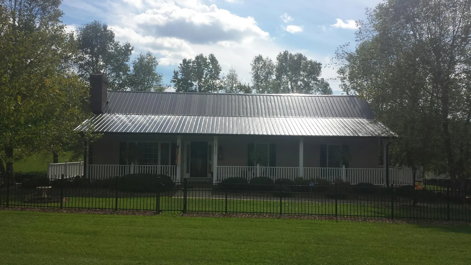 Gray metal roof on a brick ranch with a full width front porch — Gutter Guard Installation work by our crew in West Orange