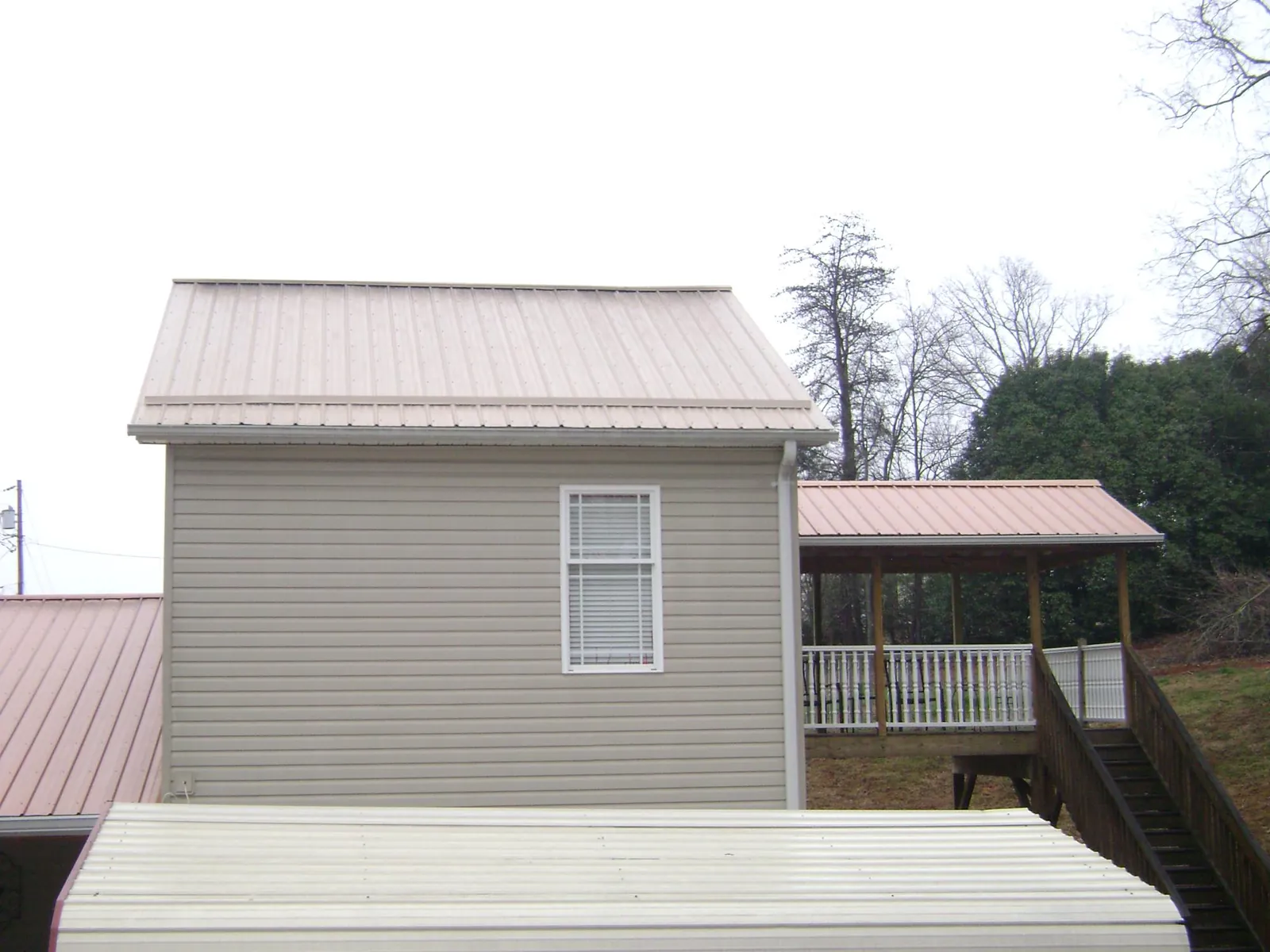 Tan metal roofs on a two story addition and attached porch, from a Roof Replacement job in West Orange