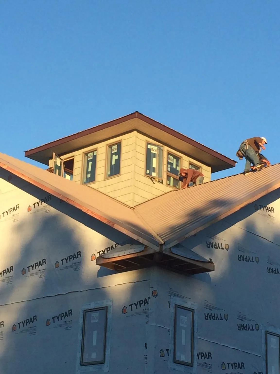 Roofers working around a rooftop cupola on a new metal roof at sunset — Roof Waterproofing in West Orange by Roofing Brothers